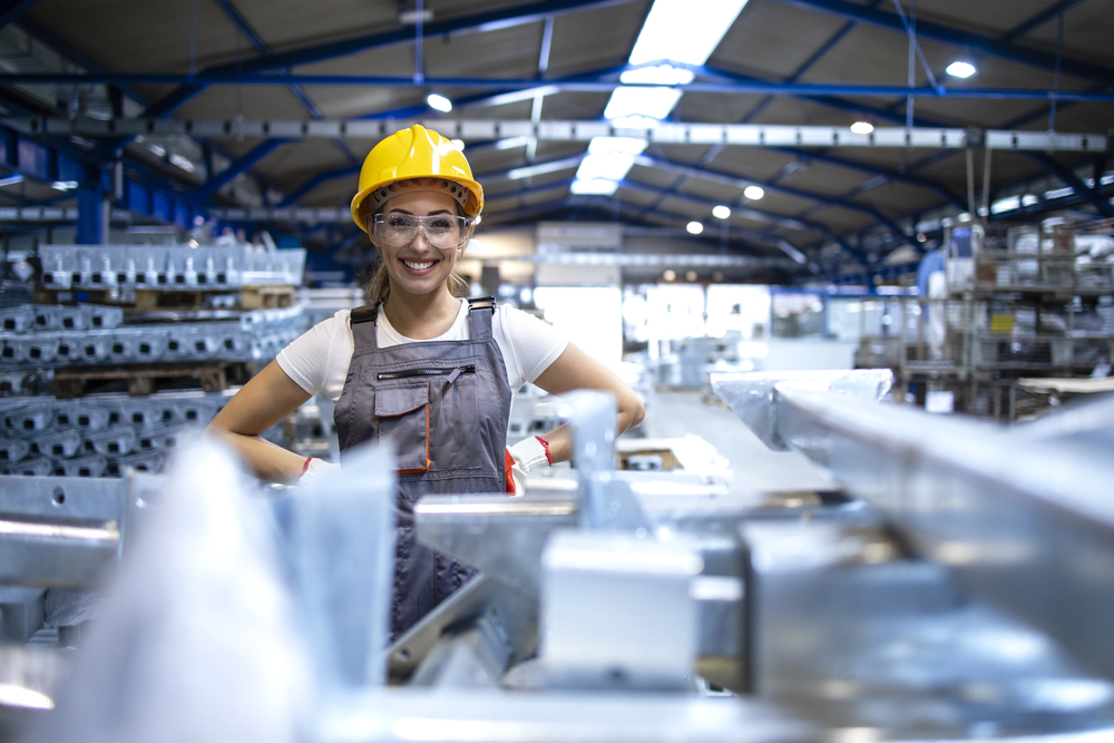 Portrait of female factory worker standing in production hall.